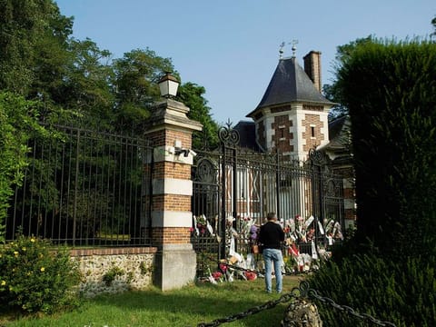 A man stands in front of the entrance of La Brulerie, the property of late French actor Alain Delon, with tribute flowers set on and next to the gate, in Douchy, central France, on August 18, 2024. 