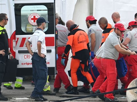 Rescuers carry a body, three days after the British-flagged luxury yacht Bayesian sank.
