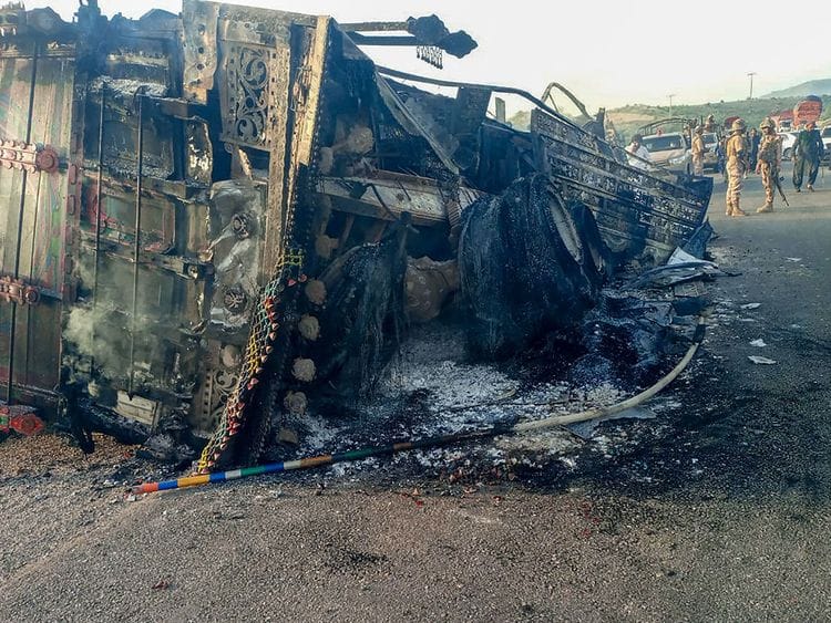 Security personnel stand guard near the charred vehicle at the shooting site on the national highway in Musakhail district, Balochistan province on August 26, 2024.  