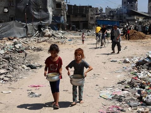 Palestinian children carry pots of soup near a food distribution point in the Jabalia refugee camp in northern Gaza Strip on August 21, 2024, amid the ongoing conflict in the Palestinian territory between Israel and Hamas.