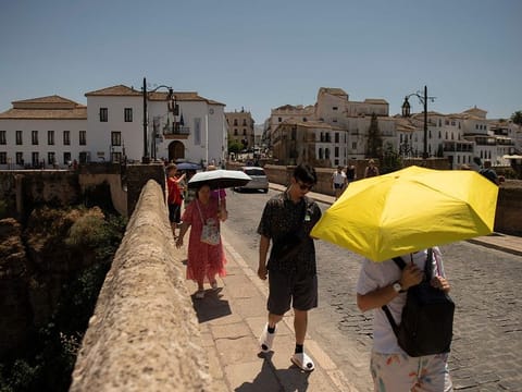 Tourist hide from the sun with umbrellas as their visit Ronda, southern Spain as the country faces the fourth heatwave of the summer.
