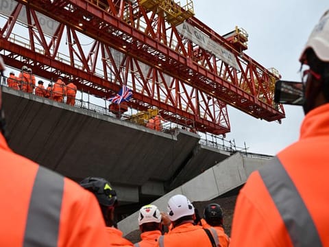 A Union Jack flag flaps in the air as workers fixe the final deck segment of HS2s 2.1-mile on the viaduct crossing the Colne Valley, in Maple Cross, north-west of London, on September 5, 2024.  