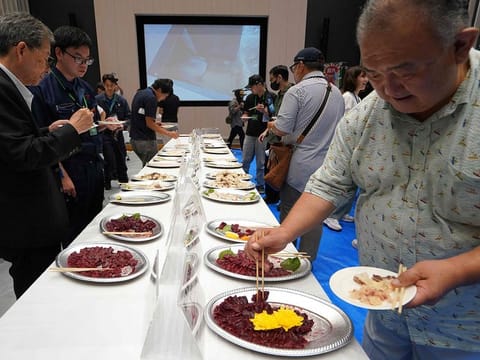 Guests taste raw meat from a fin whale at the exhibition and business meeting of domestically produced fin whales.