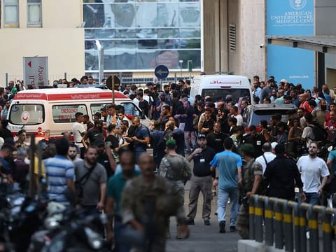 Ambulances are surrounded by people at the entrance of the American University of Beirut Medical Center.