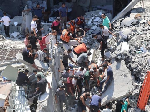 Palestinians search for survivors amids the rubble of a building, which collapsed after Israeli bombardment on a building adjacent to it, in Gaza City 