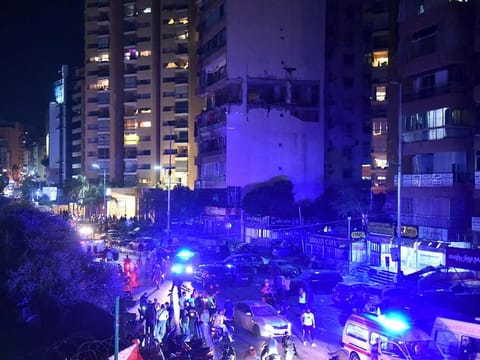 People gather outside an apartment building hit by an Israeli air strike in Beirut's Cola district, September 30, 2024. 