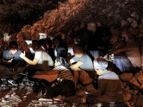 People take cover under a bridge along a highway between Kafr Qara and Baqa Al Gharbiya in northern Israel on October 1, 2024.  