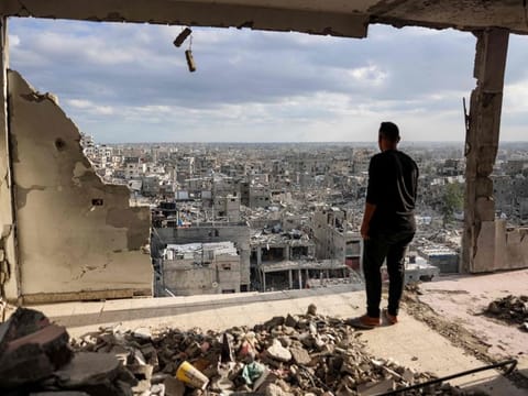 A man standing atop a heavily damaged building views other destroyed buildings in Khan Younis in the southern Gaza Strip on October 7, 2024 on the first anniversary of the ongoing war in the Palestinian territory between Israel and Hamas.  