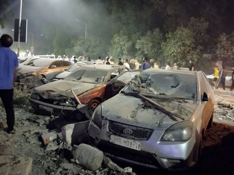 People gather by damaged vehicles at the site of a reported Israeli air strike on a residential building, where senior members of Iran's Islamic Revolutionary Guards Corps (IRGC) and Lebanese Hezbollah meet, in the Mazzeh suburb on the western outskirts of Syria's capital Damascus on October 8, 2024.  
