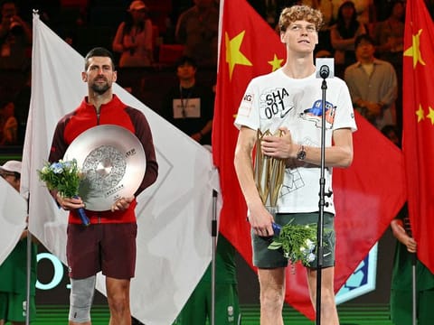 Italy's Jannik Sinner (R) speaks while holding his winner's trophy following victory against Serbia’s Novak Djokovic (L) in their men's singles final match at the Shanghai Masters tennis tournament in Shanghai on October 13, 2024.