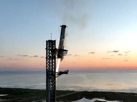 The Starship's Super Heavy Booster being grappled mid-air as it returns to the launch pad at Starbase near Boca Chica, Texas, on October 13, 2024, during the Starship Flight 5 test.