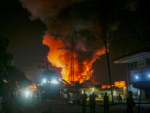 This handout picture provided by the United Nations Relief and Works Agency for Palestine Refugees in the Near East (UNRWA), shows fire and smoke billowing from the site of an Israeli air strike around tents for displaced people inside the walls of Al Aqsa Martyrs Hospital in Deir Al Balah, in the central Gaza Strip early on October 14, 2024.  