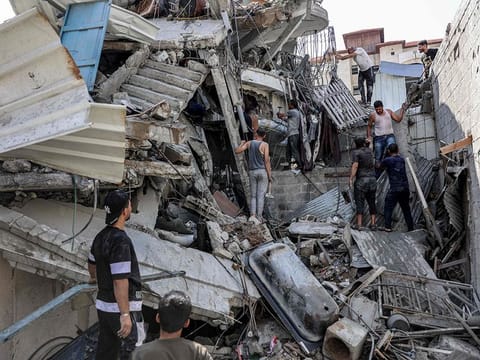 People gather outside a collapsed building as they attempt to extricate a man from underneath the rubble following Israeli bombardment in the Saftawi district in Jabalia in the northern Gaza Strip.