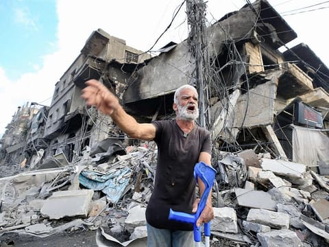 A man holds his crutches as he reacts in front amid the destruction a day after Israeli airstrikes that targeted the southern Lebanese city of Nabatieh on October 17, 2024.  