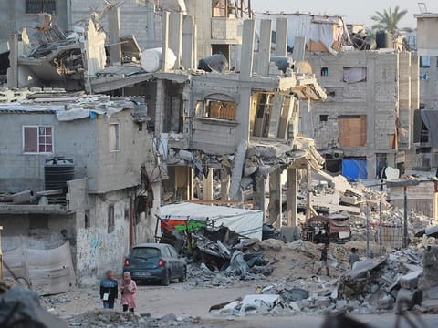 People walk past destroyed buildings in Khan Yunis in the southern Gaza Strip on October 17, 2024, amid the ongoing war between Israel and the Palestinian militant group Hamas in the besieged Palestinian territory. 