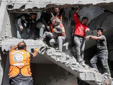 Palestinian civil defence members rescue a child following Israeli bombardment of the four-storey Muqat family house in the Zarqa neighbourhood in the north of Gaza City on October 26, 2024.