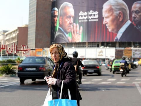 A billboard bearing pictures of Iran's President Masoud Pezeshkian, armed forces chief of staff Major General Mohammad Bagheri US President Joe Biden and Israeli Prime Minister Benjamin Netanyahu in Vali-Asr square in Tehran on October 27, 2024.  