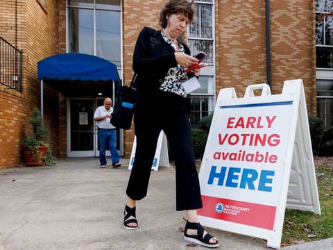 A poll watcher walks past an early voting sign at a polling location outside Flipper Temple AME during early voting in Atlanta, Georgia, US, on Sunday, Oct 27, 2024. 