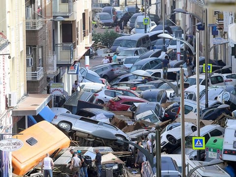 Pedestrians stand next to  piled up cars following deadly floods in Sedavi, south of Valencia, eastern Spain, on October 30, 2024. 