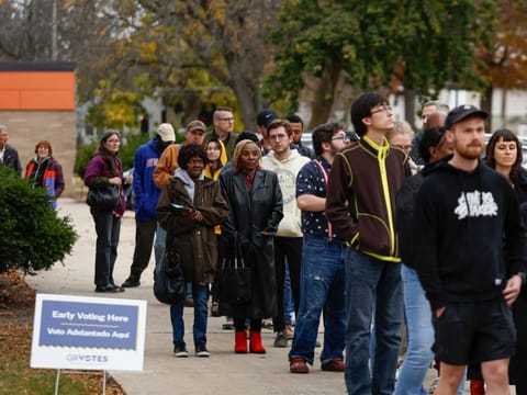 People wait in line to vote during early voting for the US general election at a polling station at Ottawa Hills High School in Grand Rapids, Michigan, on November 3, 2024.  