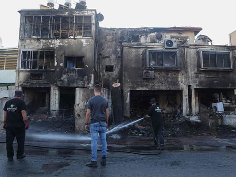 Israeli emergency and security services work clear the site where a rocket fired from Lebanon hit an area in Kiryat Ata a day earlier, in northern Israel's Haifa district on November 12, 2024.   