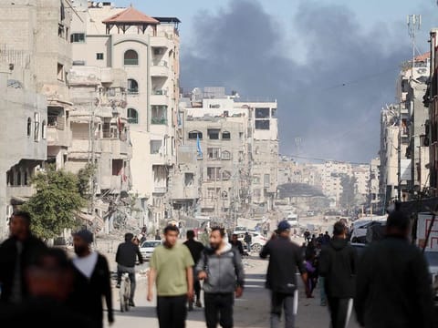 Smoke from Israeli bombardment billows as people walk at Al Jalaa street in Gaza City on November 14, 2024, amid the ongoing war between Israel and the Palestinian militant group Hamas.   