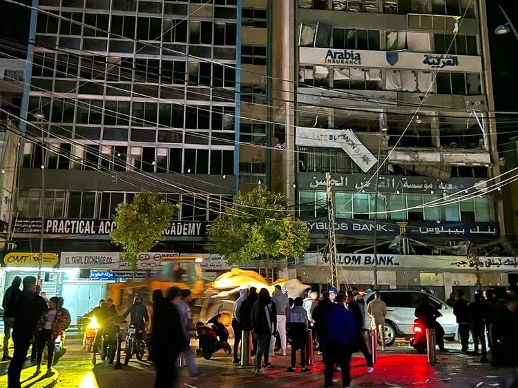 People walk at the site of an Israeli airstrike 