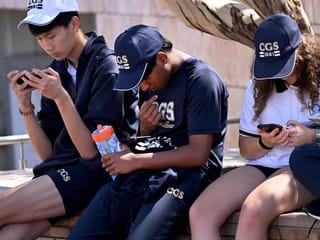 Students look at their phones in Melbourne on November 28, 2024 as Australia looks to ban children under 16 from social media with claims social media platforms have been tarnished by cyberbullying, the spread of illegal content, and election-meddling claims. Australia is among the vanguard of nations trying to clean up social media, and the age limit legislation will make it among the world's strictest measures aimed at children.  