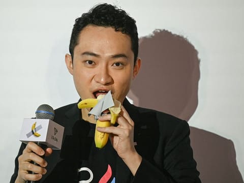 Chinese-born crypto founder Justin Sun eats a banana artwork composed of a fresh banana stuck to a wall with duct tape, in Hong Kong on November 29, 2024, after buying the provocative work of conceptual art by Italian artist Maurizio Cattelan at a New York auction for $6.2 million. 