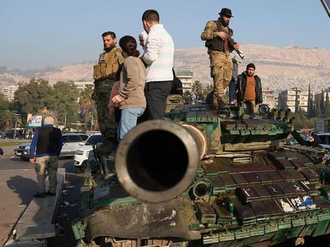 Anti-government fighters atop a tank in Damascus on December 9, 2024