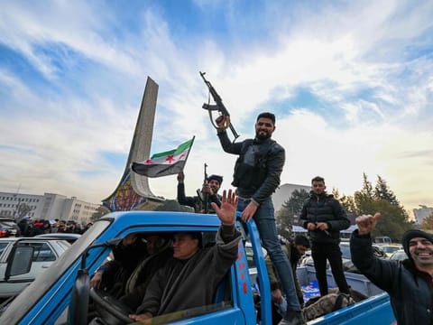 Rebels cheer from the back of a car at Umayyad Square in Damascus on December 8, 2024.  