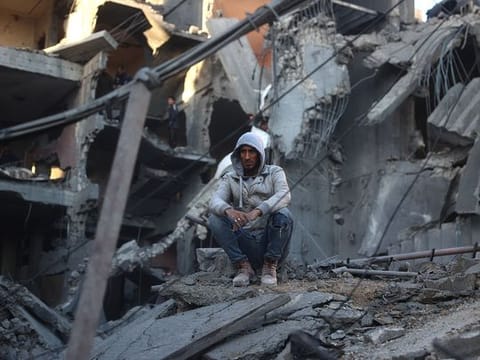 A Palestinian man sits on the rubble of a destroyed building in the Nuseirat refugee in the central Gaza Strip 