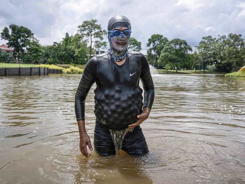 Sumadi Ibrahim, 51, walking with golf balls he recovered inside his diving suit in a pond at a course in Shah Alam, on the outskirts of Kuala Lumpur