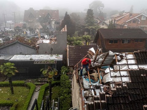 A man checks the damages on a roof caused by a plane crash at the city of Gramado, Rio Grande do Sul state, Brazil, on December 22, 2024. 