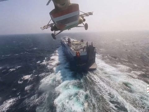 Al Houthi military helicopter flies over the Galaxy Leader cargo ship after it seized the vessel in the Red Sea in November.  