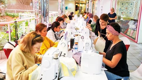Participants in the forthcoming show sew their quilts on individual machines 