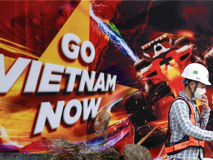 A worker walks past hoarding at the Formula One Vietnam Grand Prix race track site in Hanoi.